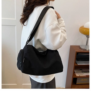 Vue détaillée du grand sac bandoulière en nylon noir avec étiquettes de mode et fermeture