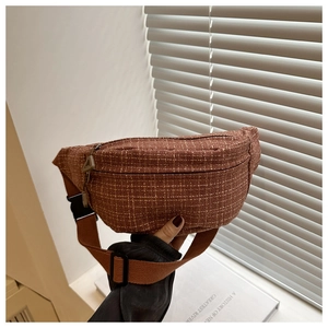 Detail of brown plaid tweed waist bag featuring adjustable canvas strap and plastic buckle