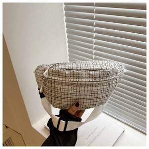 Detail of checkered tweed chest bag with zipper pockets and adjustable white strap