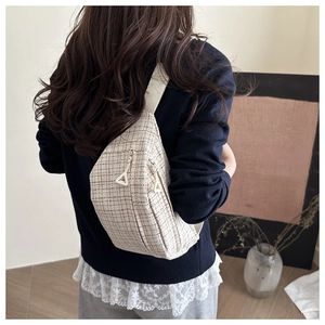 Detailed view of beige tweed crossbody bag with red-brown check pattern on female model