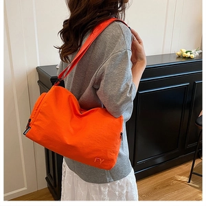 Détail du sac cabas orange montrant la broderie FY et l'étiquette sur nylon