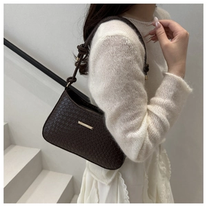Detail of dark brown shoulder bag featuring woven leather texture and gold metal buckle