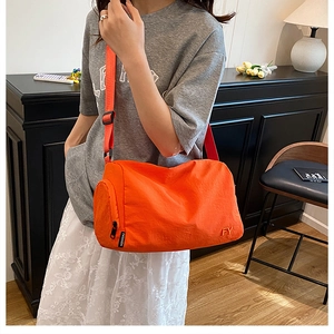 Détail du sac bandoulière en nylon orange avec sangle réglable et poche zippée