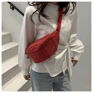Detail of red tweed crossbody bag with woven texture worn over a white shirt