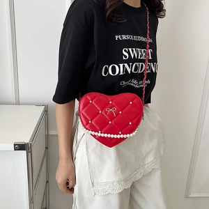 Quilted heart-shaped crossbody bag with red leather, pearl accents, and a silver bow