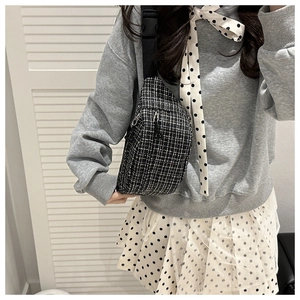 Close-up of black and white tweed texture on a stylish crossbody chest bag for women