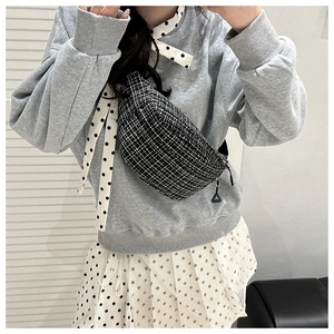 Close-up of black and white tweed crossbody bag texture with zipper detail on model