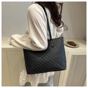 Vue détaillée d'un grand sac cabas noir avec des motifs de monogrammes gris