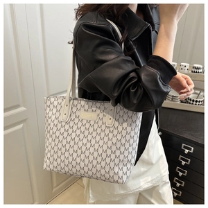 Gros plan d'un sac cabas beige avec motif M et logo métallique FASHION doré sur le devant
