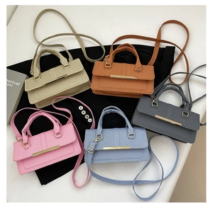 Top view of five textured small square handbags in khaki, caramel, grey, pink and blue