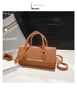 Detail of a brown textured crossbody bag with rectangular metal hardware and webbed strap