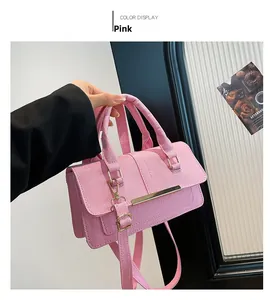 Close-up of pink woven handbag featuring gold metal clasp and matching fabric shoulder strap