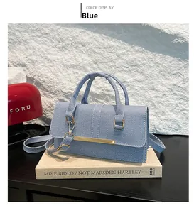 Detail of light blue denim tote bag with gold metal buckle on a black wooden table