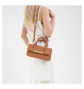 Detail of brown woven textured crossbody bag with metal accent and magnetic flap cover
