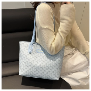 Détail du sac cabas bleu clair à monogramme avec étiquette FASHION dorée et fines lanières