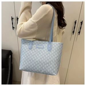Détail du sac cabas bleu clair avec motif en M et longues anses de transport