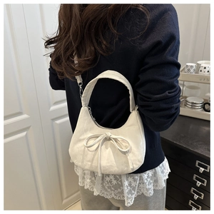 Close-up of white crescent handbag featuring a large bow and soft PU leather texture
