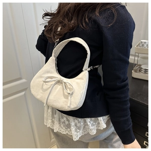 Détail du sac beige en forme de croissant avec nœud décoratif et fermeture éclair argentée