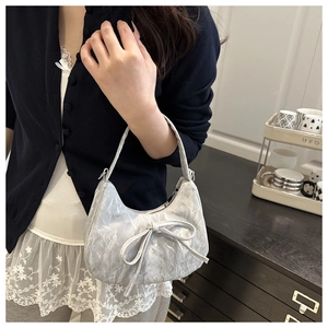 Détail du sac à bandoulière plissé argenté avec décoration de nœud et sangle