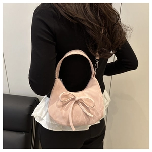 Détail d'un sac rose à nœud avec texture marbrée porté par un mannequin dans un décor épuré