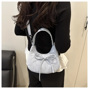 Detail of light blue crescent shoulder bag with a large bow and silver metal hardware