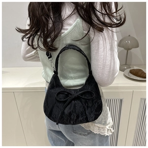 Détails du sac croissant noir à nœud montrant la texture plissée et les ferrures métal