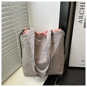 Detail of grey drawstring bucket bag with pink lining on a sunny windowsill
