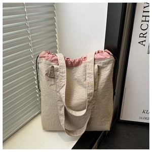 Detail of light beige pleated nylon bucket bag with pink drawstring and double handles