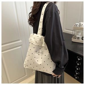 Detail of white ruffled mesh tote bag with small black floral print and woven label