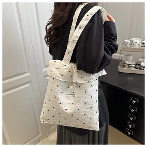 Detail of white floral tote bag featuring ruffled edges and black flower patterns