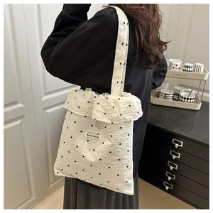 Close-up of white floral canvas tote bag featuring ruffled edges and branded woven label