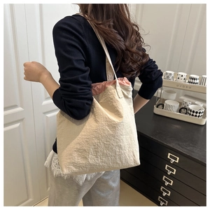 Detail of minimalist beige pleated tote bag with pink drawstring closure on a model