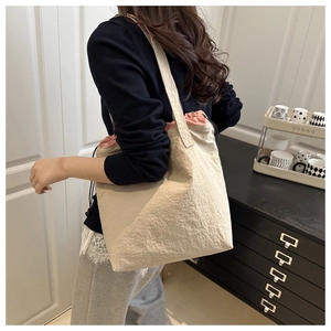 Detail view of beige drawstring bucket bag featuring soft pleated fabric and pink lining