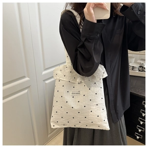 Detail of white floral canvas tote bag featuring sweet ruffled edges and brand label