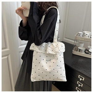 Close-up of white ruffled tote bag with black floral pattern and textured fabric