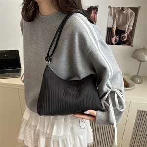 Large black pleated tote bag with vertical stripes and knotted shoulder strap