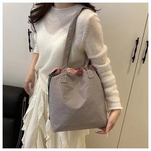 Detail of taupe drawstring bucket bag with pink lining and spacious interior