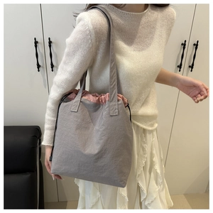 Detailed view of grey nylon drawstring tote bag with contrast pink lining and long strap