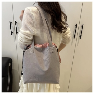 Gray nylon tote bag with pink drawstring closure worn by model for daily commute