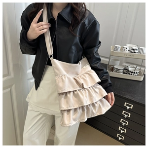 Detail of off-white tiered ruffle tote bag featuring a pleated cake skirt design on strap