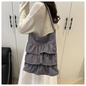Detail showing grey tiered ruffle tote bag with multiple pleated layers and wide strap