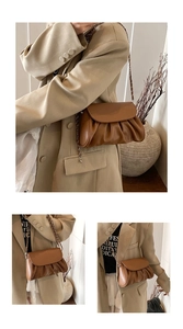 Detailed view of brown ruched cloud bag featuring pleated texture and chain strap