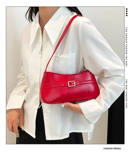 Detail showing bright red glossy leather shoulder bag with decorative metal buckle and strap