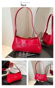 Detail view of the red glossy shoulder bag featuring a decorative buckle and sleek finish