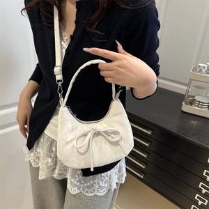 Sac à main blanc en demi-lune avec nœud et relief, porté par un mannequin en bandoulière