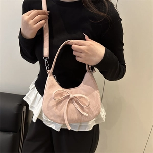 Sac à bandoulière rose en forme de croissant avec nœud porté par un mannequin en studio