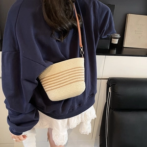 French style woven straw bucket bag with brown leather strap for elegant crossbody use