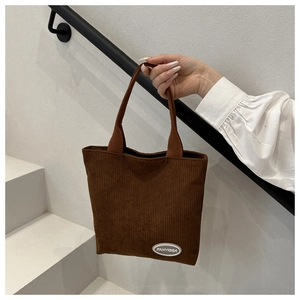 Detail of a brown corduroy bucket bag with Fanyissa label and reinforced handles