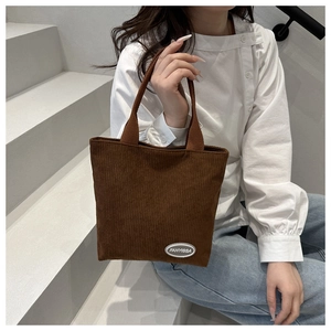 Detailed texture of brown corduroy tote bag with FANYISSA brand label in a lifestyle setting