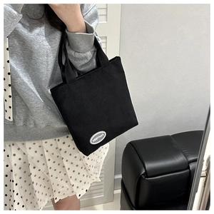 Close-up of black corduroy tote bag featuring the FANYISSA logo patch and soft texture